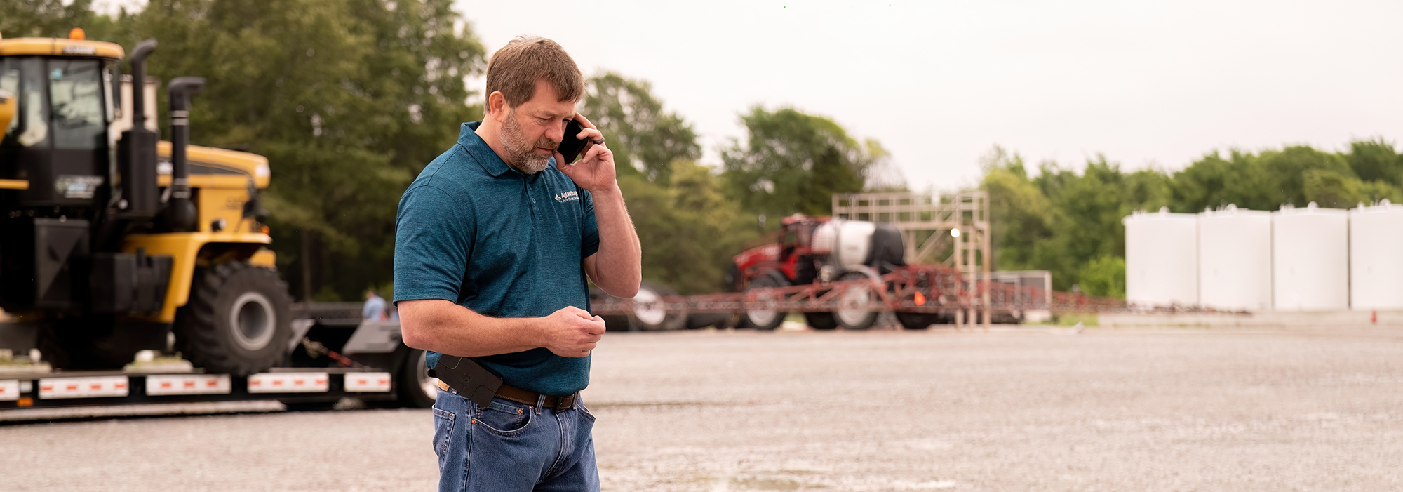 man on phone next to tractor in the country