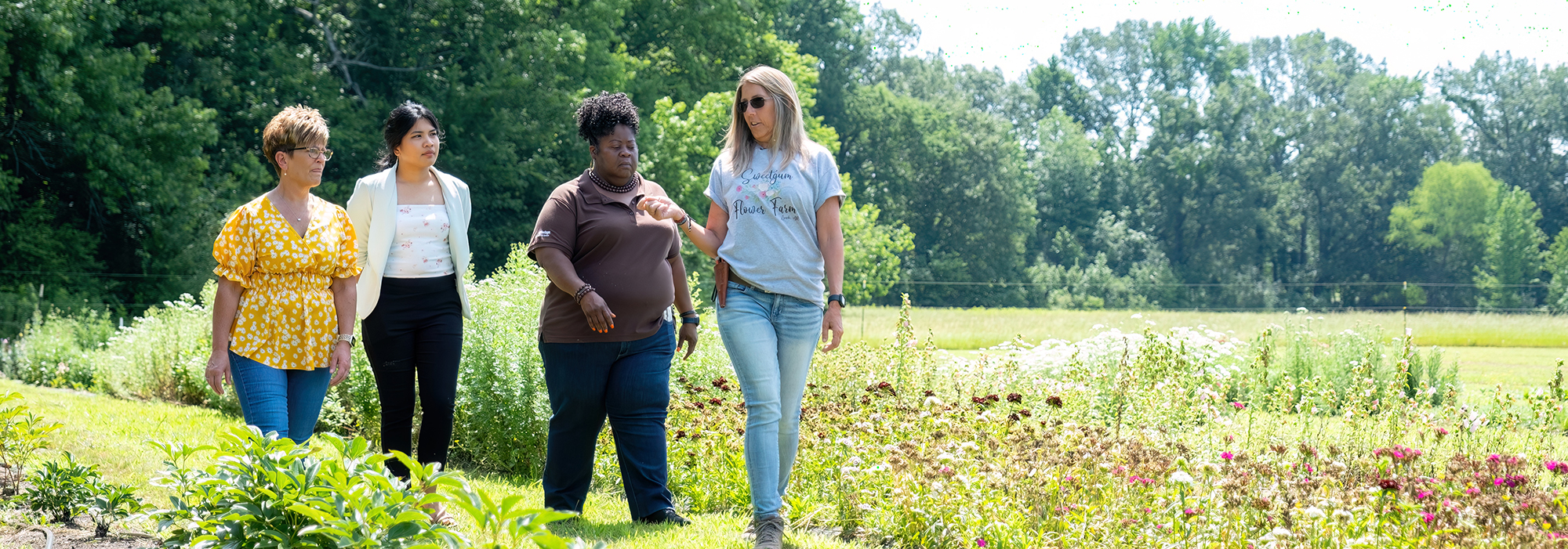 group of people talking and walking through flower field 