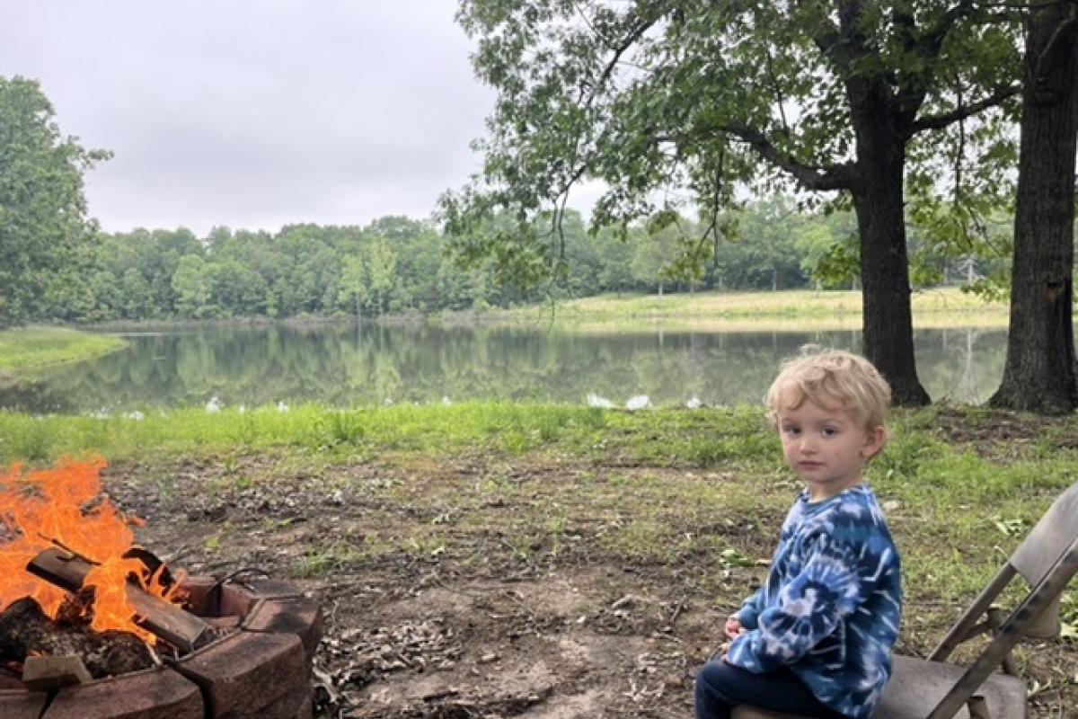 This was taken at our ranch outside of Ash Flat .. It’s my Grand Nephew sitting by the fire pit with the lake in background..